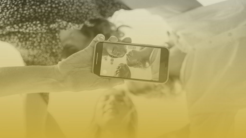 Grupo de jóvenes grabando un video con el móvil, representando la creación de contenido auténtico para redes sociales.